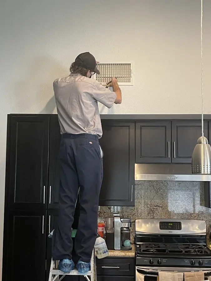 Technician inspecting an air vent during HVAC service in Aubrey